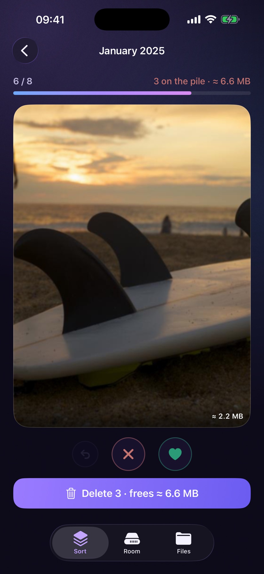 Sort mode in Nana’s Photo Cleaner, showing January 2025. A photograph of a surfboard on a beach at sunset fills the card, marked roughly 2.2 megabytes. The counter above reads 6 of 8 with three on the pile and about 6.6 megabytes waiting, and a purple button at the bottom reads Delete 3, frees about 6.6 megabytes.
